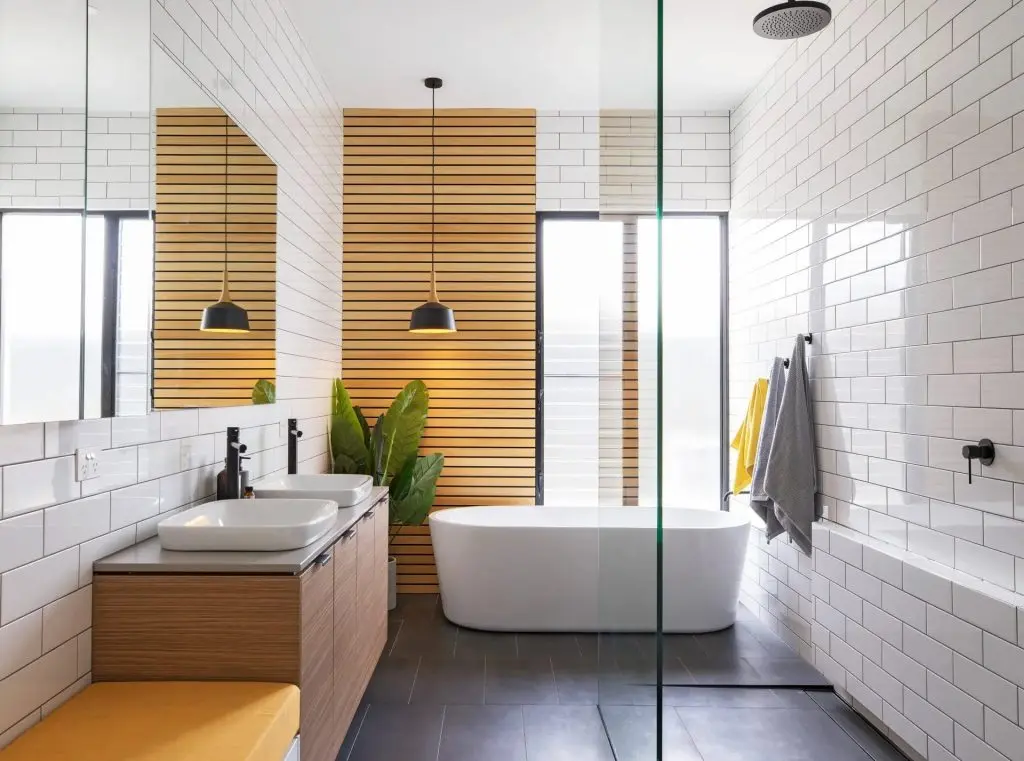 Modern bathroom with a freestanding tub, double vanity, glass shower, and white subway tile