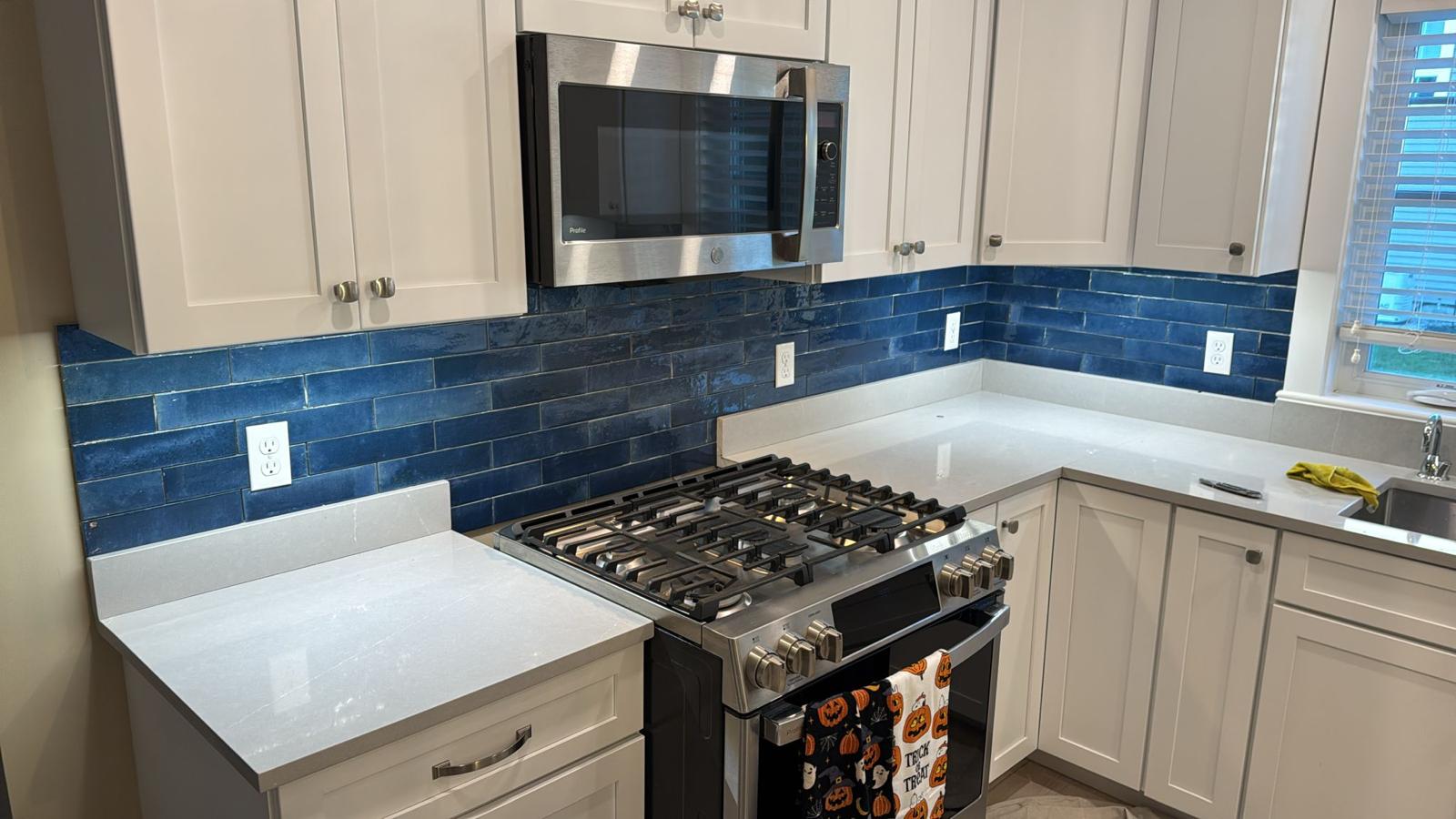 Completed blue tile kitchen backsplash with white cabinets and quartz countertops by Luxe Revamp
