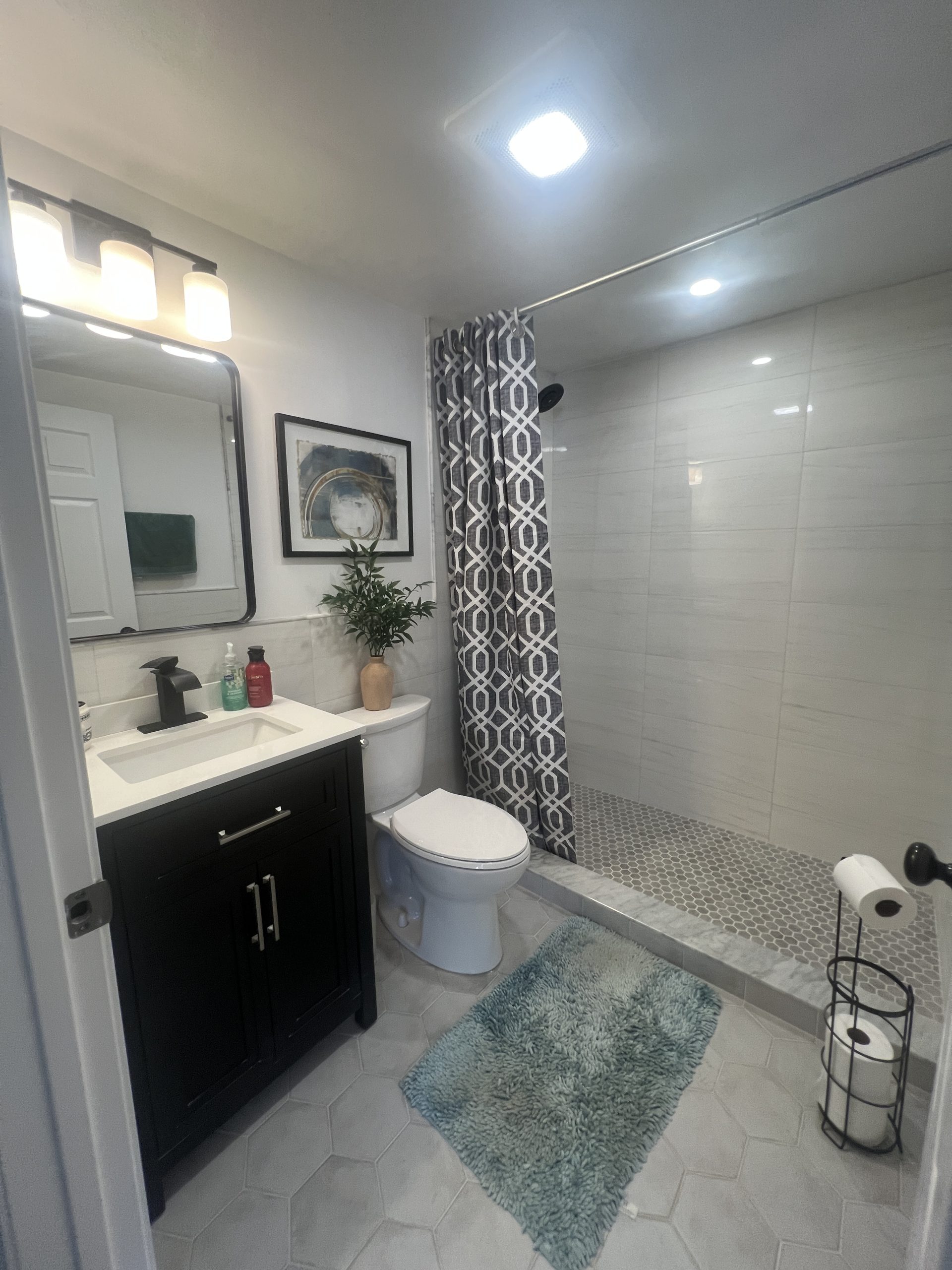 Completed gray and white bathroom renovation with vanity and walk-in shower by Luxe Revamp