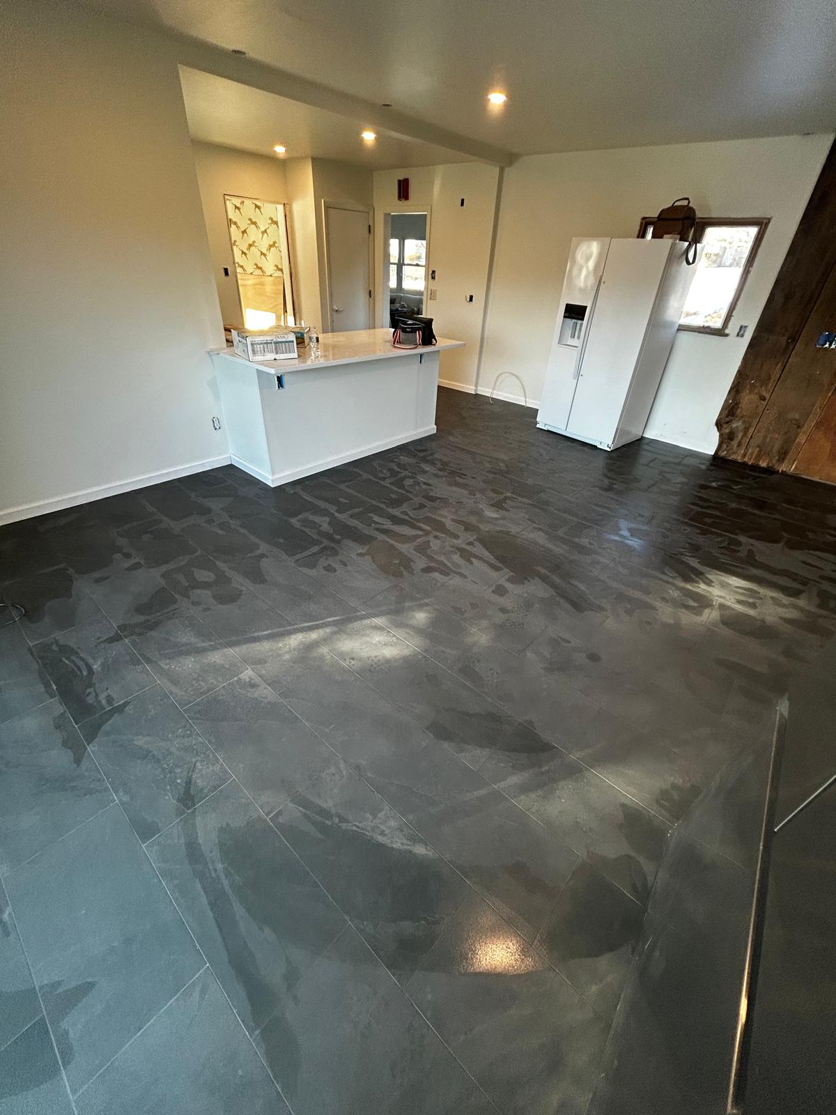 Completed dark large-format flooring installation in an open living space by Luxe Revamp
