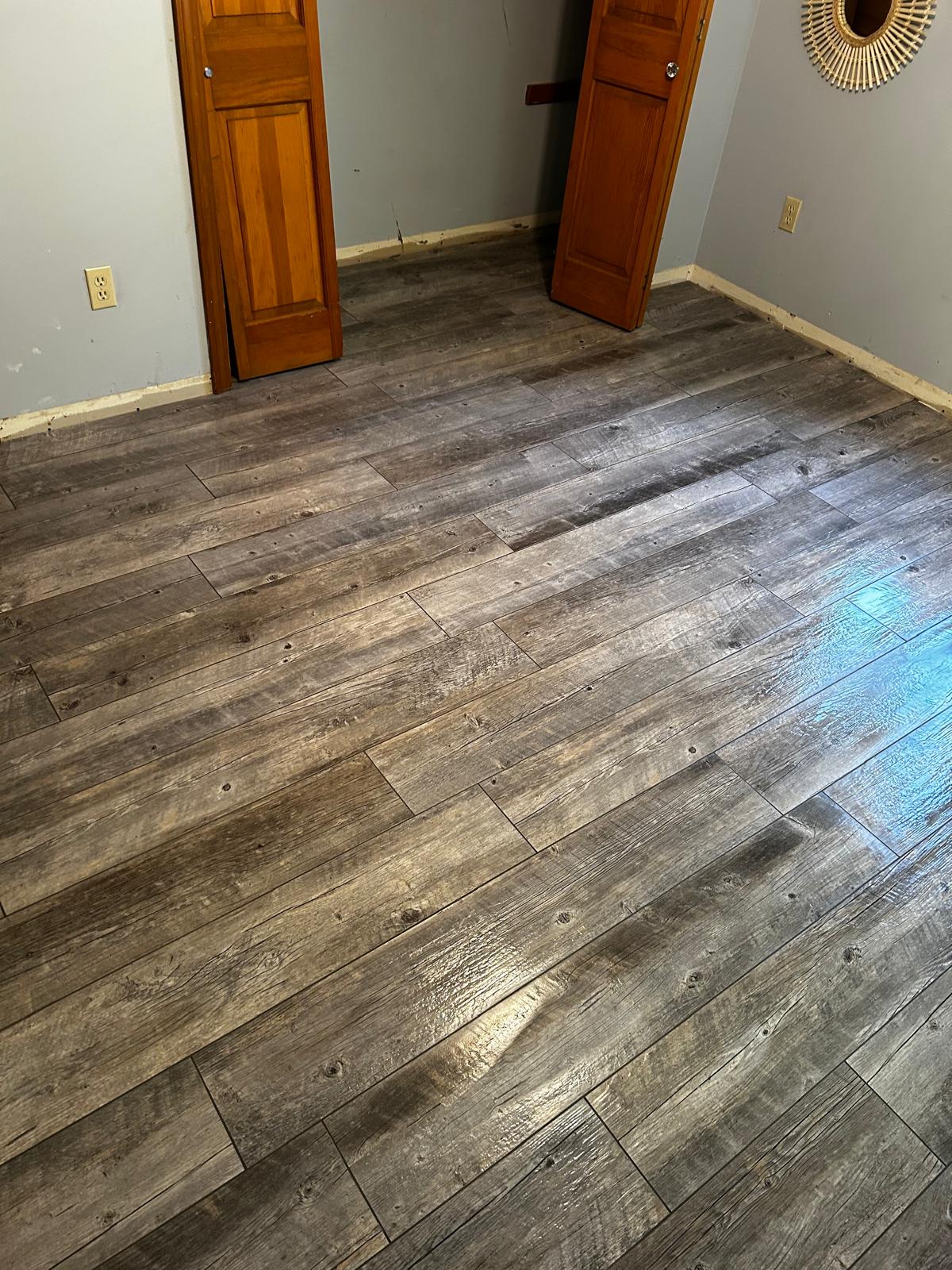 Completed gray plank flooring installation in a renovated room by Luxe Revamp