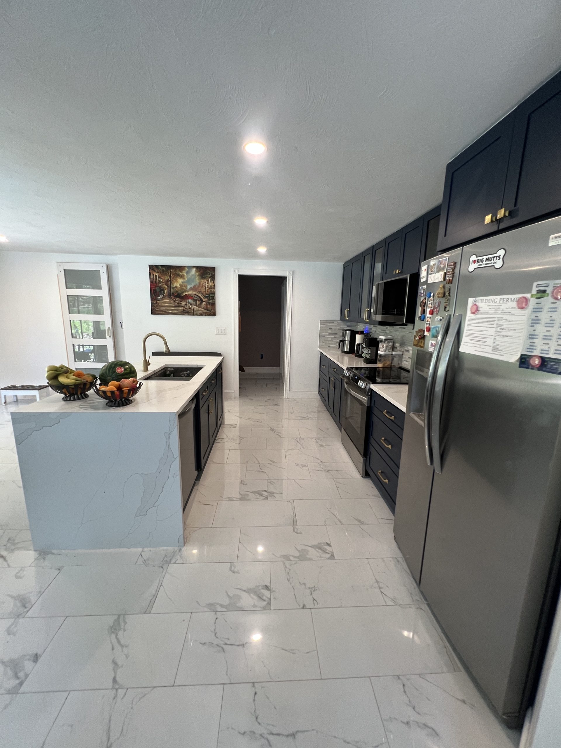 Completed luxury kitchen with navy cabinets, waterfall island and polished tile flooring by Luxe Revamp