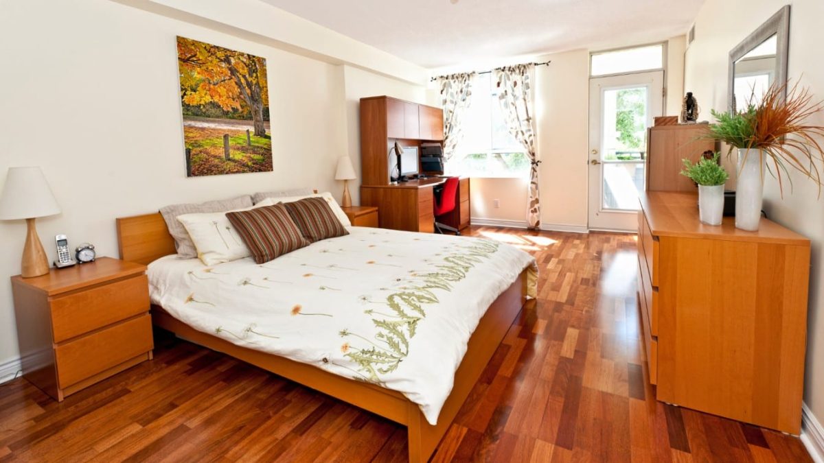 Finished warm-toned hardwood flooring in a bright furnished bedroom