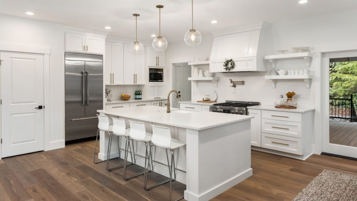 Warm wood flooring in a bright white kitchen with a large center island